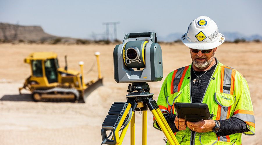 Surveyor using a T7 in front of a grading machine